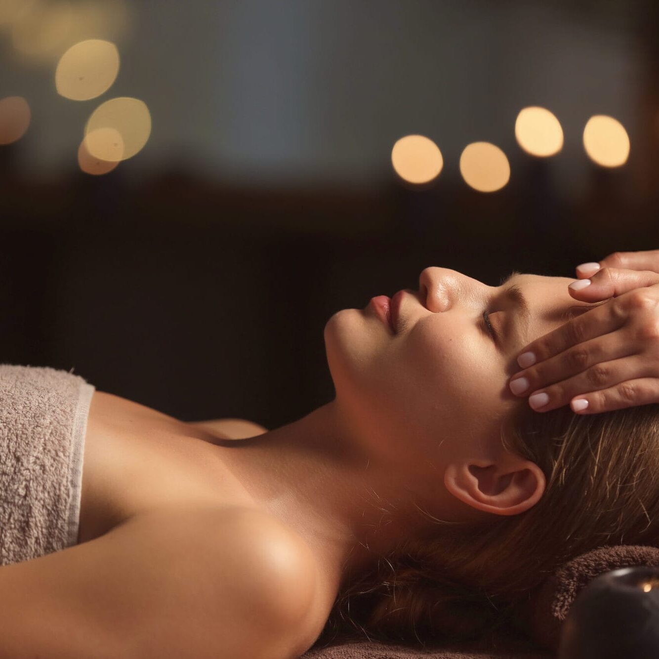 Beautiful young woman receiving facial massage in spa salon